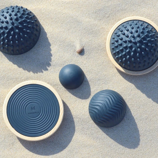 Makarlu Lotus textured massage domes and timber bases arranged on sand for outdoor mobility and sensory therapy.
