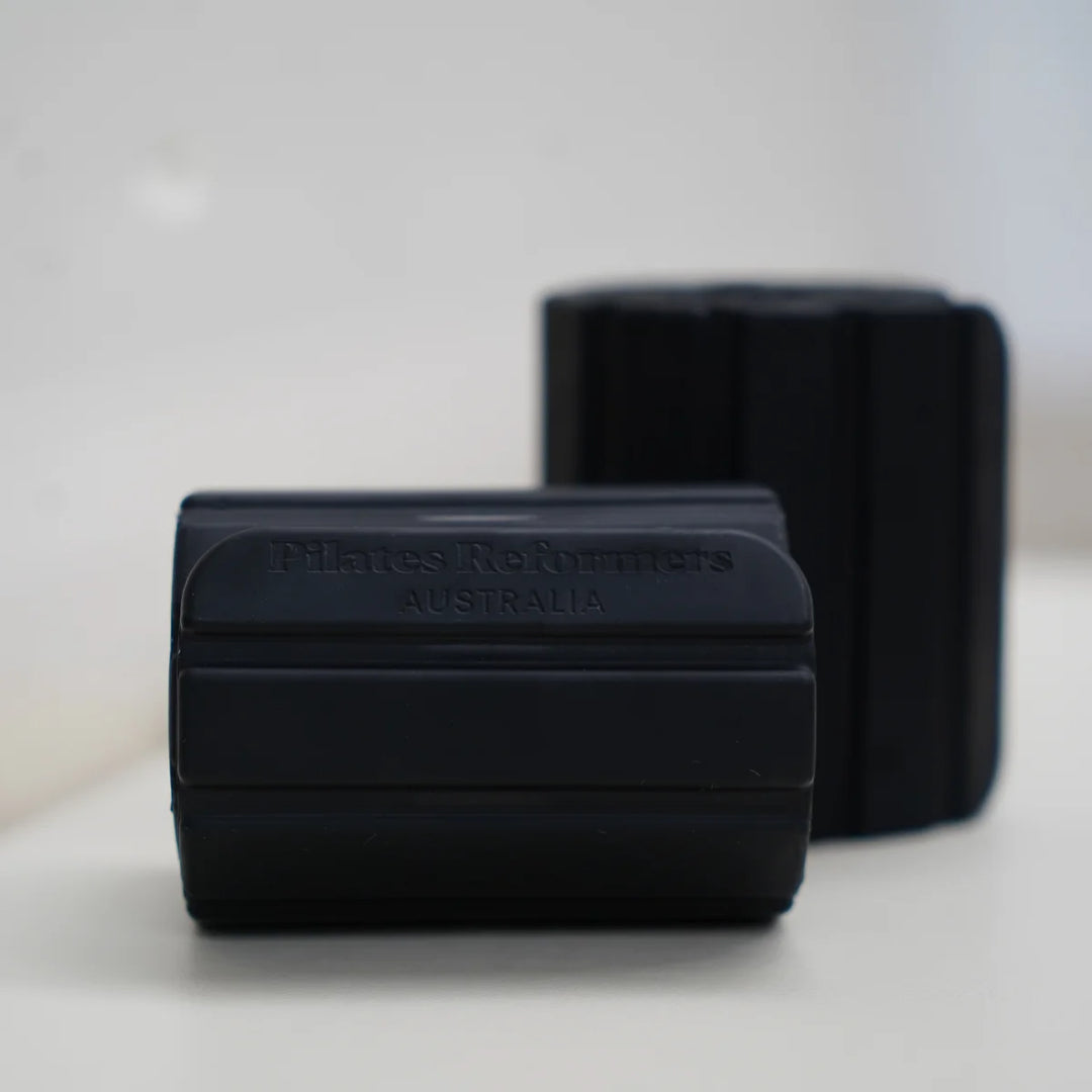 Two black magnetic weights rollers on a light surface