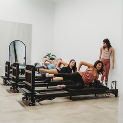 Group of women using Pilates reformers in a studio setting.