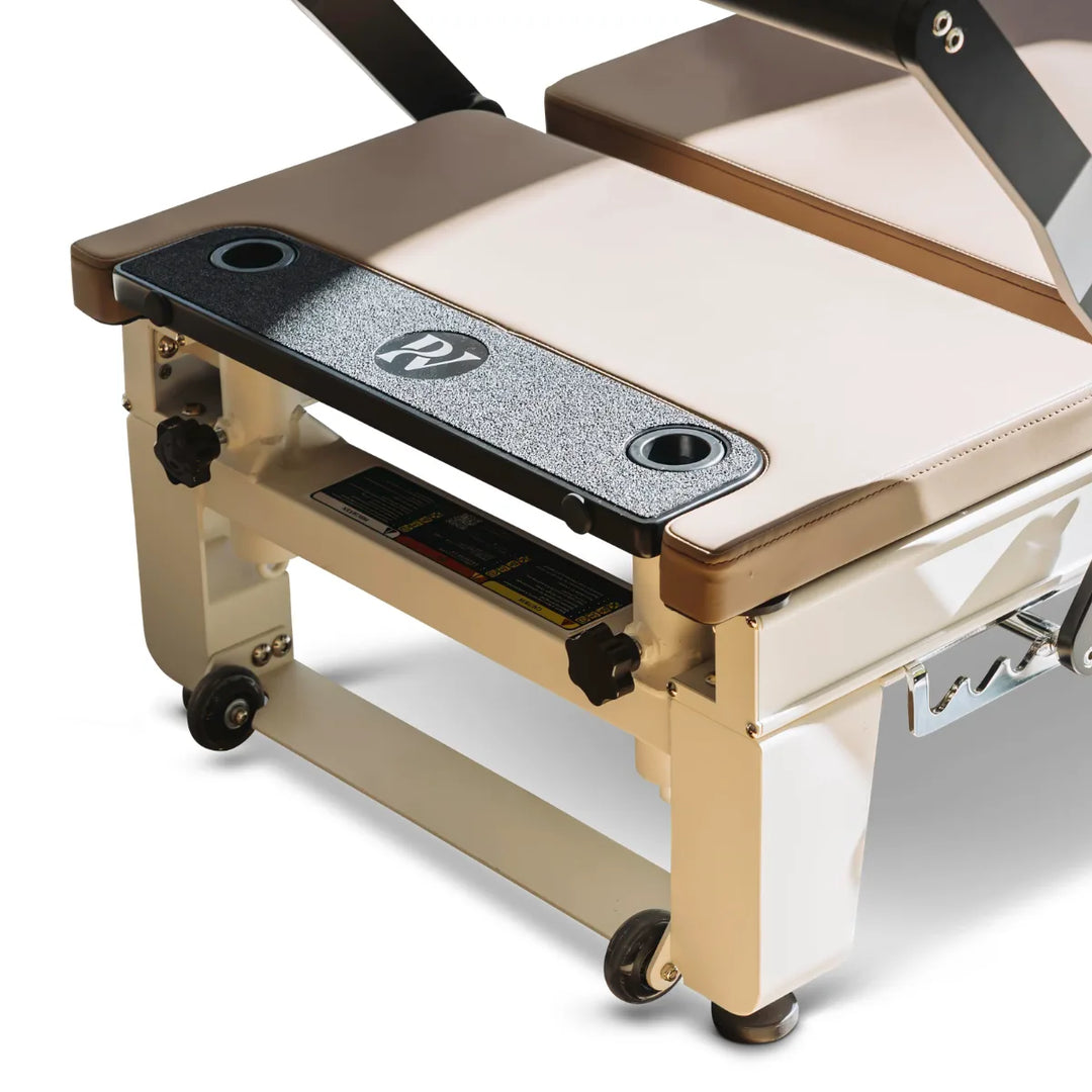 Close-up of a Pilates reformer machine platform extender with white lower legs and black caster wheels.