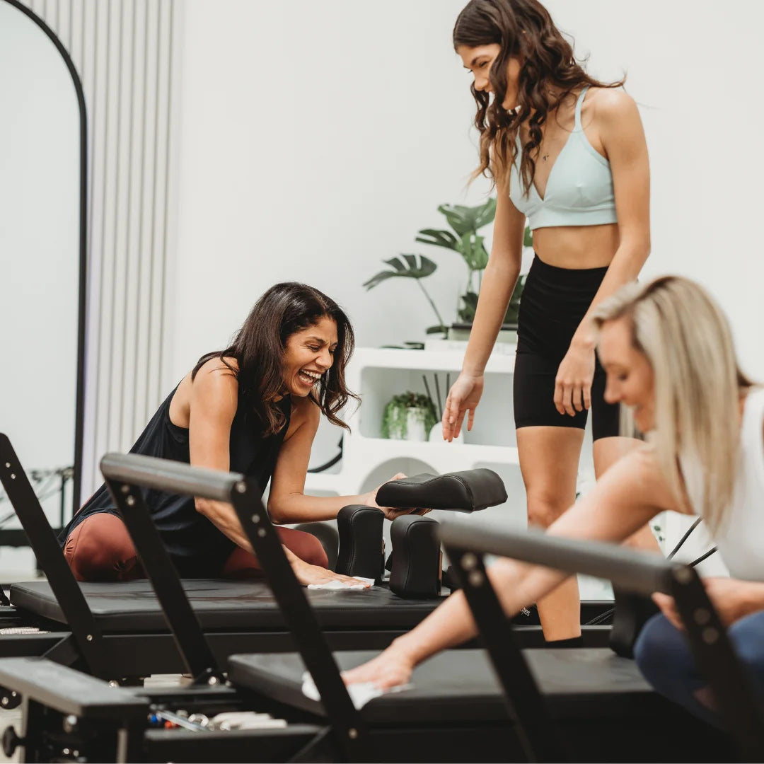 women in Pilates studio wiping Reformers with PGW StudioCare Wipes