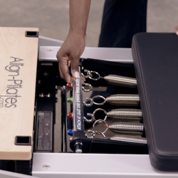 person adjusting align-pilates patented rapid change reformer spring bar