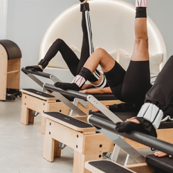 People using Pilates reformers in a studio setting