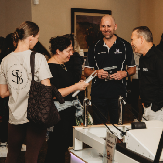 Customers talking to Pilates Reformers Australia representatives at The Pilates Expo
